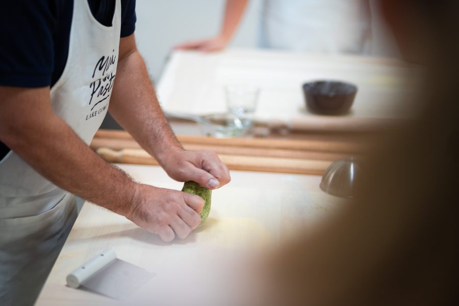 Mani che impastano il panetto verde agli spinaci durante il corso di ravioli a Como