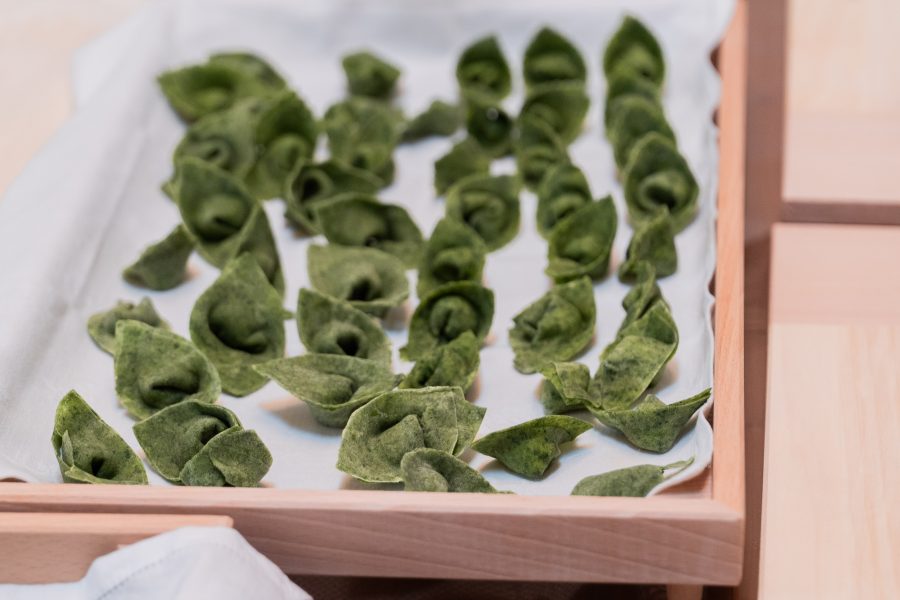 Vassoio di ravioloni verdi di ricotta appena chiusi, fatti dagli ospiti del corso